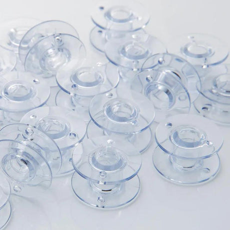 Clear Brother SA156 bobbins viewed from the top and side.