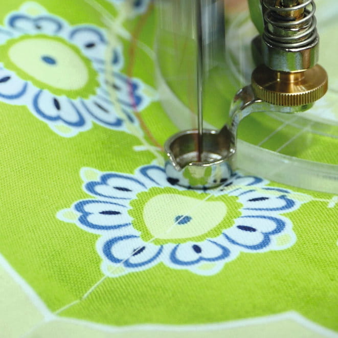 Ruler foot beside the edge of a clear quilting ruler on patterned fabric.