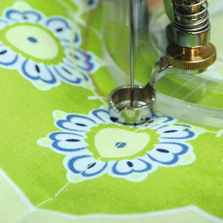 Ruler foot beside the edge of a clear quilting ruler on patterned fabric.